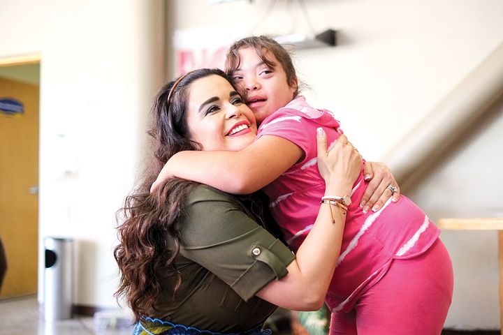 child with down syndrome hugging her teacher