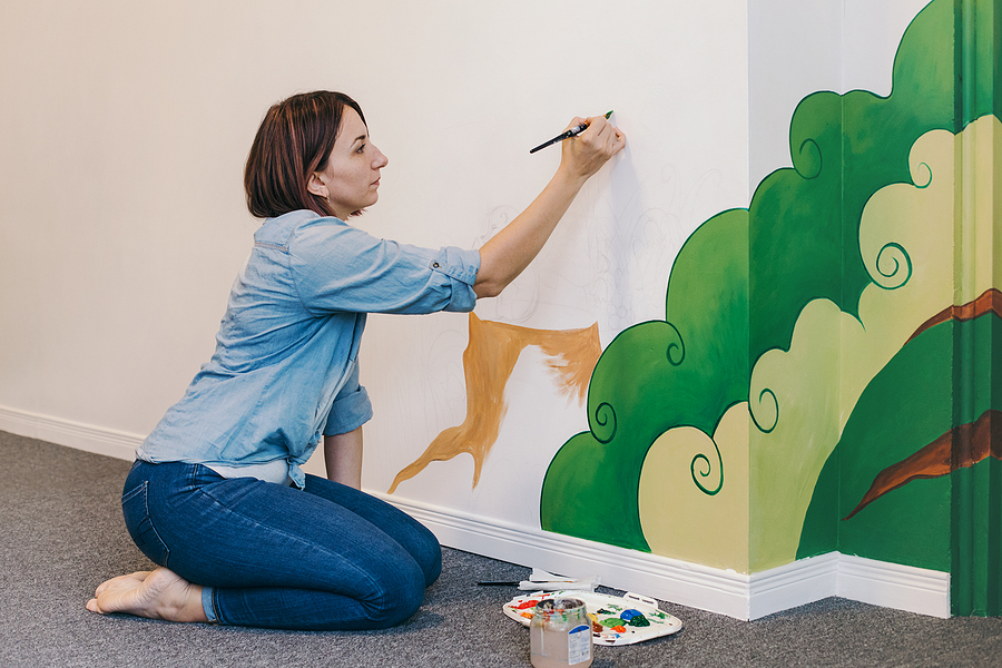 Female mural painter outlining in a wall